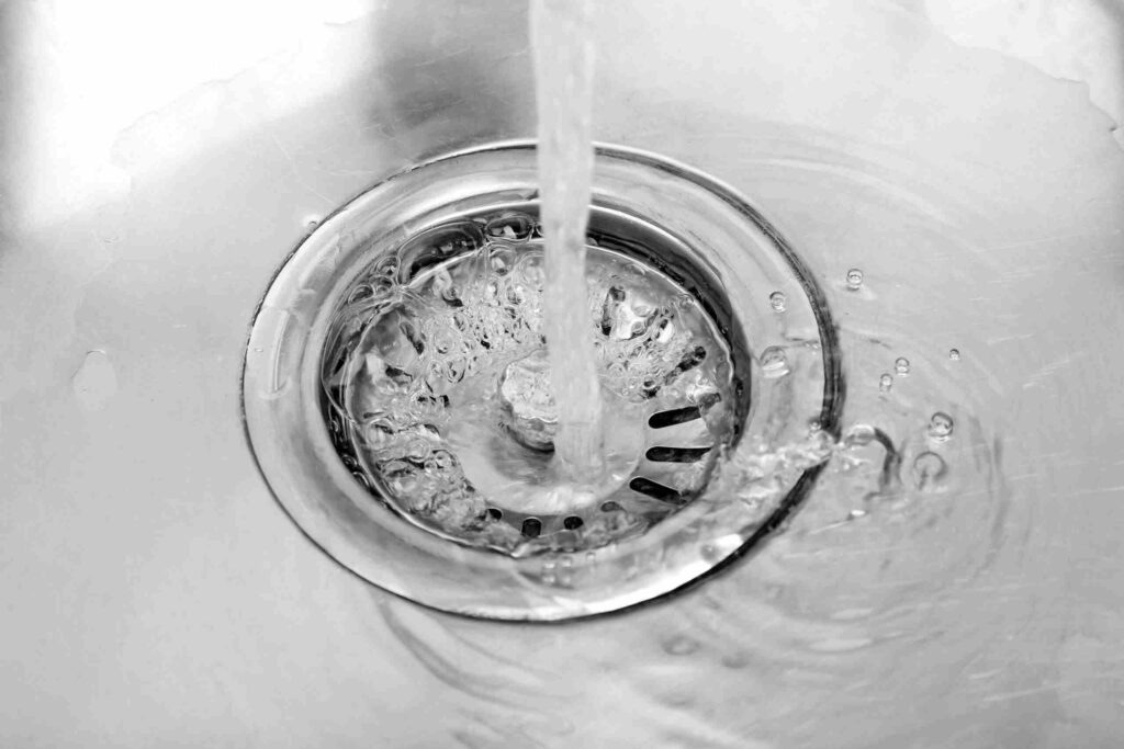 closeup of water flowing down a stainless steel sink drain